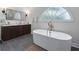 A luxurious bathroom with an oval tub, a double sink with dark cabinets, and a large window at 1811 Fountain Hill Ct, Duluth, GA 30097