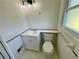 Bright bathroom featuring a white toilet, vanity, and tiled walls, complemented by a modern light fixture and window at 2682 Pineland Ave, Atlanta, GA 30340
