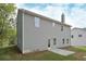 Rear exterior view of a new home with gray siding, chimney, and a small concrete patio at 496 Charleston Pl, Villa Rica, GA 30180