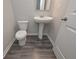 Half-bathroom features a pedestal sink, toilet, and wood-look flooring at 496 Charleston Pl, Villa Rica, GA 30180