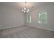 Bright living room features carpet flooring, a modern chandelier and two windows at 496 Charleston Pl, Villa Rica, GA 30180