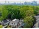 This aerial shot shows the house, its surrounding lush greenery, and a view of the city skyline in the distance at 1272 N Highland Ne Ave, Atlanta, GA 30306