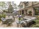 This backyard features a patio with a dining table and seating, an outdoor grill, and lush landscaping for relaxation at 1272 N Highland Ne Ave, Atlanta, GA 30306