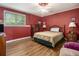 Cozy bedroom boasts warm red walls, wood floors, and comfortable furnishings at 4855 Regency Sw Trce, Atlanta, GA 30331