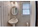 Small bathroom featuring a pedestal sink, decorative mirror, and striped wallpaper at 5800 S Richland Creek Rd, Buford, GA 30518