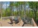 A wooden back deck features an outdoor dining set and bench seating, perfect for enjoying the wooded view at 6565 Scottsfield Trce, Cumming, GA 30028