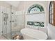 Bright bathroom with modern glass shower and large soaking tub beneath a beautiful arched window at 6565 Scottsfield Trce, Cumming, GA 30028