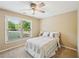 Cozy bedroom with a ceiling fan, carpet flooring, and natural light from a large window at 6565 Scottsfield Trce, Cumming, GA 30028