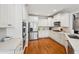 Well-lit kitchen includes stainless steel appliances, white cabinets, and hardwood flooring at 6565 Scottsfield Trce, Cumming, GA 30028