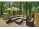 A beautiful wood back deck features modern patio furniture, a grill, and an umbrella for entertaining at 535 Emerald Pkwy, Sugar Hill, GA 30518