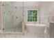 Bright bathroom with a glass shower and a modern standalone tub featuring a window view at 535 Emerald Pkwy, Sugar Hill, GA 30518