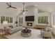Bright living room features a fireplace, vaulted ceilings, ceiling fans, and multiple windows with wooded views at 535 Emerald Pkwy, Sugar Hill, GA 30518