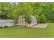 Shed on a lush lawn, complemented by mature trees and a white fence at 1320 Pinyon Pl, Lawrenceville, GA 30043