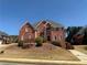 Elegant two-story red brick home featuring a manicured lawn, gray roof, and symmetrical window design at 240 Flowers Cove Ln, Lilburn, GA 30047