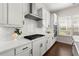 Updated kitchen featuring modern appliances, white cabinets, herringbone backsplash, and a stainless steel range hood at 1074 Heyward Way, Alpharetta, GA 30009