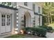 Close-up of the front entrance of the home featuring arched doorway, manicured bushes, and sconce lighting at 1658 Mount Paran Nw Rd, Atlanta, GA 30327