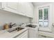 Well-lit laundry room with modern washer and dryer, a utility sink, and white cabinets at 1658 Mount Paran Nw Rd, Atlanta, GA 30327