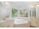 Bathroom featuring a large soaking tub beneath a bay window, dual vanities, and tile flooring at 1721 Druids Se Xing, Conyers, GA 30013