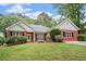 Charming brick home with a well-manicured lawn, complemented by lush greenery and flowering bushes at 1721 Druids Se Xing, Conyers, GA 30013