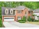 Traditional brick home with dormer windows, arched entryway, attached garage and lush landscaping at 1894 Whitehawk Ct, Lawrenceville, GA 30043