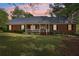 Inviting brick home featuring a cozy front porch, manicured lawn, and mature trees under a picturesque evening sky at 2301 Sharon Se Ct, Conyers, GA 30013