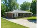 Charming brick home featuring mature trees, an extended driveway, and a bay window with black shutters at 724 Camelot Way, Norcross, GA 30071
