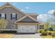 A two-car garage featuring carriage door hardware is attached to a home with gray siding and trimmed with tan accents at 1410 Bluestone Dr, Cumming, GA 30041