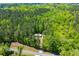 Aerial view of a house with metal roof, nestled in a dense, green forest near a quiet road at 1530 Mcbrayer Rd, Temple, GA 30179