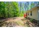 A home's peaceful backyard with lush greenery and a small red deck offers a tranquil outdoor retreat at 1530 Mcbrayer Rd, Temple, GA 30179