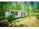 Charming one-story home with black shutters and a red front door surrounded by mature trees and lush landscaping at 1530 Mcbrayer Rd, Temple, GA 30179