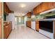 Well-lit kitchen features tile flooring, wooden cabinetry, and full appliances with an open doorway beyond at 1530 Mcbrayer Rd, Temple, GA 30179