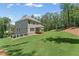 Spacious backyard with lush green grass with home exterior, deck and wooded backdrop at 1005 Liberty Springs Dr, Woodstock, GA 30188