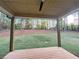 Covered porch with wooden deck overlooks a level and landscaped backyard surrounded by mature trees at 1005 Liberty Springs Dr, Woodstock, GA 30188