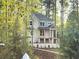 Charming two-story home with a brick facade and inviting front porch surrounded by mature trees at 1005 Liberty Springs Dr, Woodstock, GA 30188