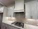 Kitchen showcasing white cabinets, granite countertops, herringbone backsplash, and stainless steel gas range at 1005 Liberty Springs Dr, Woodstock, GA 30188