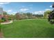 Large, well-maintained backyard with green grass, mature trees, and a pathway leading to a red barn at 4790 Hyde Rd, Cumming, GA 30040