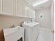 Functional laundry room featuring white cabinets, a utility sink, and modern washer and dryer at 4790 Hyde Rd, Cumming, GA 30040