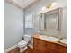 Charming powder room featuring wooden vanity, gold mirror, and unique floral wallpaper border at 4790 Hyde Rd, Cumming, GA 30040