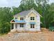 New two-story home under construction with yellow siding and a covered front porch, surrounded by lush trees at 1025 Liberty Springs Dr, Woodstock, GA 30188