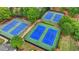 Aerial view of four well maintained blue and green tennis courts in a community surrounded by trees at 1263 Whisperwood Ln, Lawrenceville, GA 30043