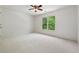 Bright bedroom featuring white walls, carpet, a ceiling fan, and a large window overlooking lush greenery at 2160 Waters Ferry Dr, Lawrenceville, GA 30043