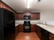U-shaped kitchen featuring wood cabinets, black appliances, and laminate countertops at 415 Village Way, Woodstock, GA 30188