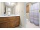 Bathroom with a wood vanity, ample counter space, and a shower with a patterned curtain at 1488 Rivermist Sw Dr, Lilburn, GA 30047