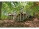 Multi-level wooden decks with stairs lead down to a shady backyard surrounded by mature trees at 7320 Oak Arms Dr, Villa Rica, GA 30180