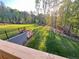 Grassy backyard with a black fence, concrete retaining wall, and mature trees at 1021 Liberty Springs Dr, Woodstock, GA 30188