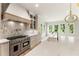 Bright kitchen featuring a stainless steel range, custom hood, island with farm sink and quartz countertops at 117 Owens Mill Pl, Canton, GA 30115