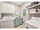 Bright laundry room featuring a utility sink, washer, dryer, and ample shelving for storage at 700 Winterwind Way, Roswell, GA 30075