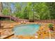 A backyard swimming pool is surrounded by a stone patio and mature trees at 700 Winterwind Way, Roswell, GA 30075