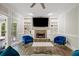 Cozy living room featuring a stone fireplace, built-in bookshelves, and two blue armchairs at 2355 Twelvestones Dr, Roswell, GA 30076