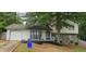 Charming split-level home featuring a stone facade, attached garage, and mature trees in the front yard at 6193 Charring Cross Ct, Lithonia, GA 30058